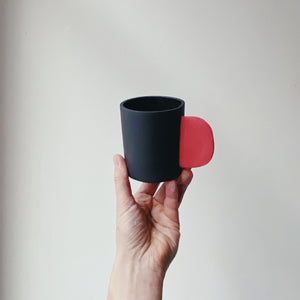 Tasse schwarz mit rotem Henkel