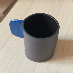 Tasse schwarz mit blauem Henkel
